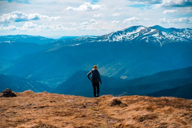 Gezgin, gün batımında karla kaplı dağların çarpıcı manzarasına bakıyor..
