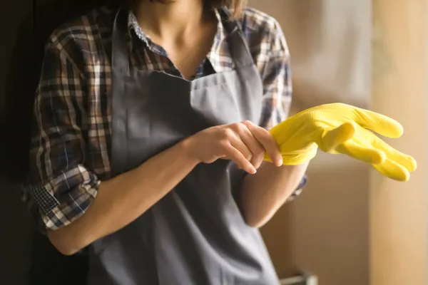 Uma mulher em luvas de borracha amarela faz trabalhos domésticos — Fotografia de Stock
