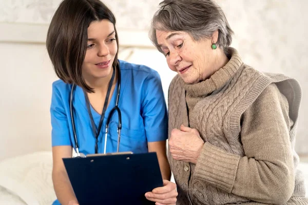Young nurse is caring for an elderly 80 year-old woman at home. — Stock Photo, Image