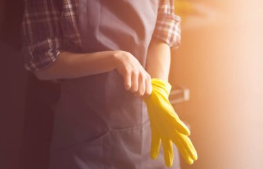 Sarı lastik eldivenli bir kadın ev işi yapar.