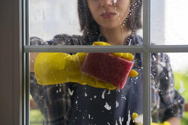 Kadın pencereleri deterjanla yıkıyor..