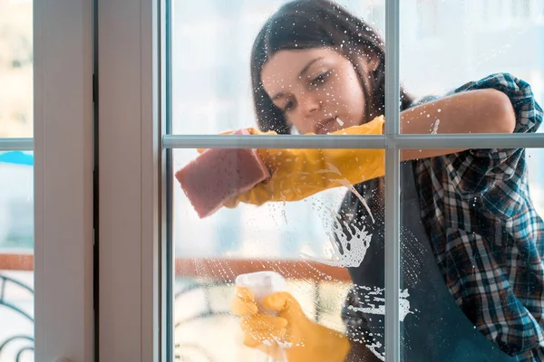 Vrouw wast de ramen met een wasmiddel. — Stockfoto