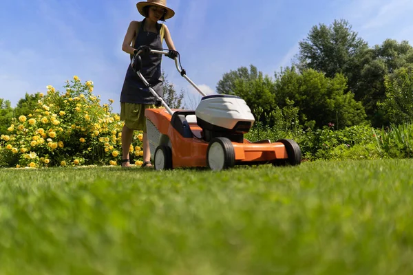 Um jardineiro mulher está cortando grama com o cortador de grama, vista inferior — Fotografia de Stock