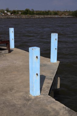 Zincirli beton çubuk iskeleye kanca, Mavi Jetty direği, güneş ışığıyla mavi beton iskele sütunları.