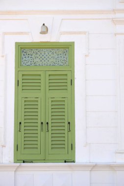 Tozlu beyaz antik bina cephesi Güzel yeşil ahşap pencereli.