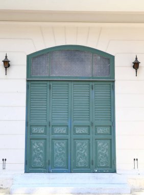 Tozlu beyaz antik bina cephesi Güzel yeşil ahşap pencereli.