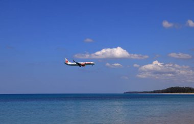 Uçak ya da yolcu uçağı THAI LiON Air Boing 737-900ER sahilin yanındaki havaalanına iniyor. Uçak deniz sahilinde son derece alçaktan uçuyor..