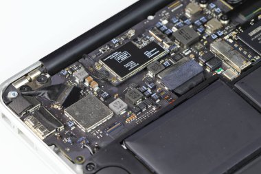 Onarılan dizüstü bilgisayar, anakart, kablosuz ağ modülü, pil ve SSD görünür.