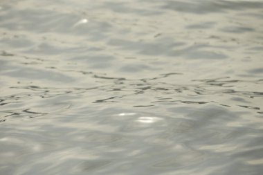 Parlak su ve yumuşak dalgaların dokusu. Suda parlayan arka plan. Güneş parlayan ve dalgalanan deniz suyu. Güçlü ve barışçıl doğa kavramı.