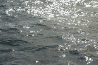 Parlak su ve yumuşak dalgaların dokusu. Suda parlayan arka plan. Güneş parlayan ve dalgalanan deniz suyu. Güçlü ve barışçıl doğa kavramı.