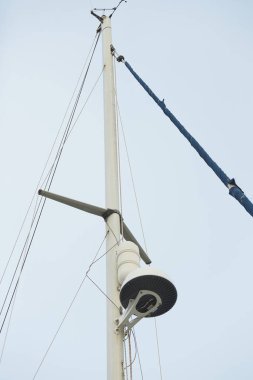 Mavi gökyüzünde bulutlu seyrüsefer ekipmanlarıyla beyaz lüks bir yatın üst kısmında.