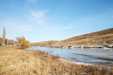 Kışın huş ağacı ve donmuş nehirle güzel doğal manzara.