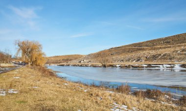 Kışın huş ağacı ve donmuş nehirle güzel doğal manzara.