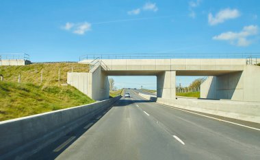Otoyolda, İrlanda 'da arabaların arka manzarası. Metal güvenlik bariyeri ya da tırabzanı olan yol. Bulutlu mavi gökyüzünün altındaki asfaltta arabalar. Otoyol trafiği.