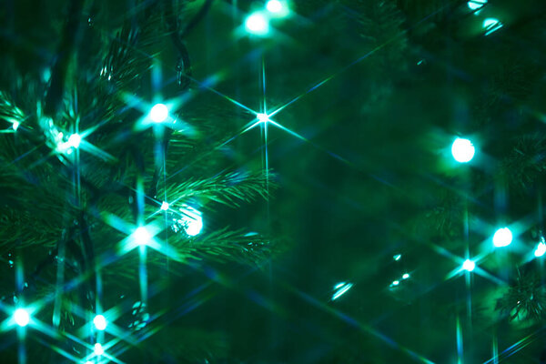 Закрытие праздничных электрических голубых гирлянд на елочной ветке с украшением елки и сладкими конфетами. Конфетка висит на ветке рождественской елки