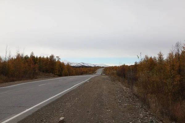Estrada de asfalto que vai para a distância em torno de uma curva — Fotografia de Stock