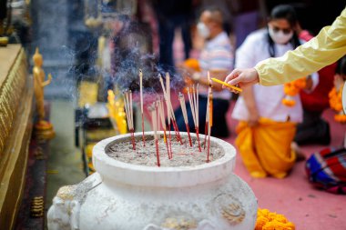 Bayan el feneri mumu ve büyük kavanozdaki tütsüye yakından bakın. Bilinmeyen insanların bulanık arkaplanı Tayland 'daki kutsal pagoda içinde Buda Stupa' ya ibadet etmeye gelir..