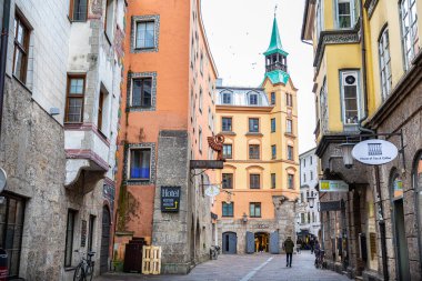 Innsbruck, Avusturya - 3 Kasım 2019: İnsanlar alışveriş ve restoran alanında klasik tarzda renkli binalarla çevrili eski sokak geçidinde yürüyorlar.