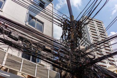 Bangkok, Tayland - 13 Şubat 2022: Bangkok 'ta çözülmesi gereken ilk öncelikli sorun olan binaların önündeki meşgul ve birbirine dolanmış elektrik kabloları.