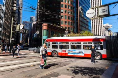 San Francisco, California, ABD - 27 Eylül 2019: Kırmızı otobüs iş yerlerinin arka planında trafik varken insanlar yaya geçidini geçiyor.