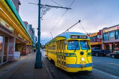 San Francisco, California, ABD - 28 Eylül 2019: Balıkçı rıhtımındaki sarı elektrikli otobüs parkları, pazar alanının arka planında gün batımında hizmet vermeye hazır.