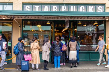 Seattle, Washington, ABD - 9 Ekim 2019: Pike Place Market 'in en klasik ve popüler mağazası olan Starbucks' ta uzun kuyrukta bekleyenler.