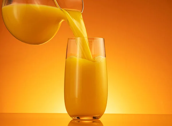 Sumo de laranja derramando em vidro com respingo — Fotografia de Stock
