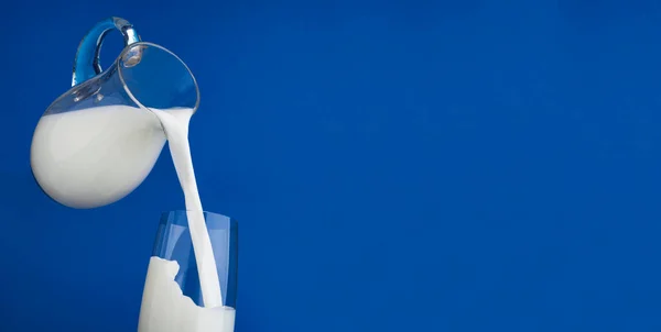 Verter leche con salpicadura sobre fondo azul — Foto de Stock