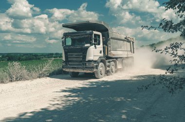 Endüstriyel çöp kamyonu, taşların taşınması, tozlu yolda yolculuk. Kariyer işi