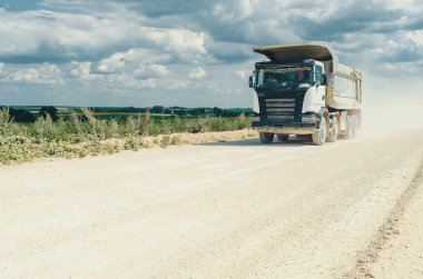 Endüstriyel çöp kamyonu, taşların taşınması, tozlu yolda yolculuk. Kariyer işi. Bulutlu gökyüzü