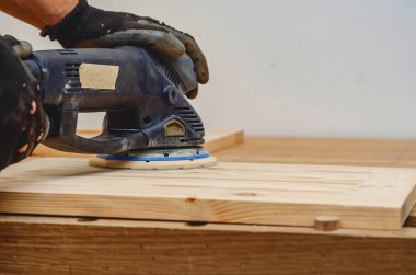 Joiner 'ın aletleri. Elle tutulan elektrikli zımpara ile ahşap bir tahtayı zımparalıyorum.
