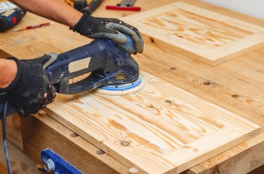 Joiner 'ın aletleri. Elle tutulan elektrikli zımpara ile ahşap bir tahtayı zımparalıyorum.