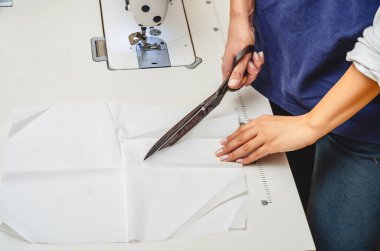 Klasik terzi makası beyaz kumaşı kesti. Kadın elleri..
