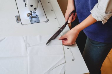 Klasik terzi makası beyaz kumaşı kesti. Kadın elleri..