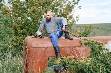 Duygusal duruşu olan Viking savaşçısı. Koluna yakın metal miğfer. Tarihi fotoğraf konsepti