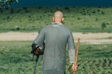 Fırtına öncesi yaz sahasının dramatik bir fotoğrafı. Zincirli zırhlı bir adam sahada yürüyor. Dikiz aynası. Yağmur damlaları.