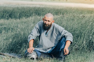 Yaz tarlasında ortaçağ kıyafetleri giymiş bir adamın portresi. Viking zırhı. Metal başlık ve zincir zırh.