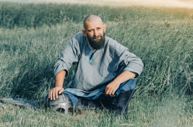 Yaz tarlasında ortaçağ kıyafetleri giymiş bir adamın portresi. Viking zırhı. Metal başlık ve zincir zırh.