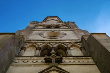 Mavi gökyüzünün arka planındaki terk edilmiş şatonun alt manzarası. Kadim taş haç, pencere kemerleri, taş sütunlar. Ortaçağ mimarisi.