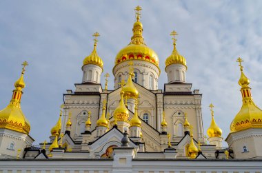 Bulutlu gökyüzüne karşı Ortodoks Hıristiyan dini binasının haçlı altın kubbeleri. Alt manzara. Pochaiv. Ukrayna, 2022