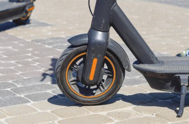 Şehir merkezindeki kaldırım taşlarının üzerine park edilmiş elektrikli scooter. Motosikletle şehirde dolaşıyorum. Tekerlek yakın.