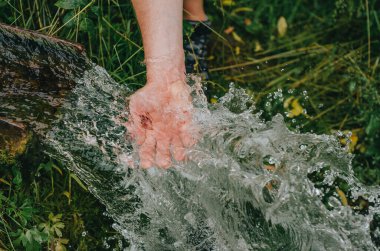 Saf kaynak suyu akıntısı. İnsan eli kristal gibi serin baharda.