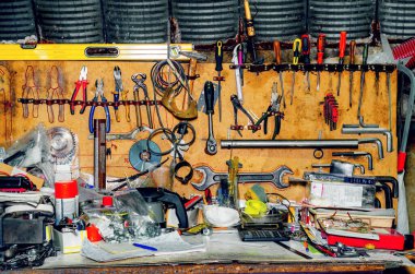 Workshop with tools. Collection of various repair tools hanging on wall above desktop.