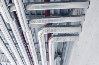 Tavan altına monte edilmiş metal borular modern üretim tesisinde termal yalıtım ile kaplıdır.