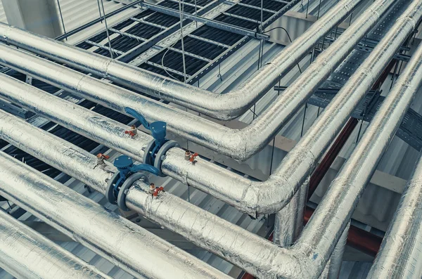 Tavan altına monte edilmiş metal borular modern üretim tesisinde termal yalıtım ile kaplıdır.