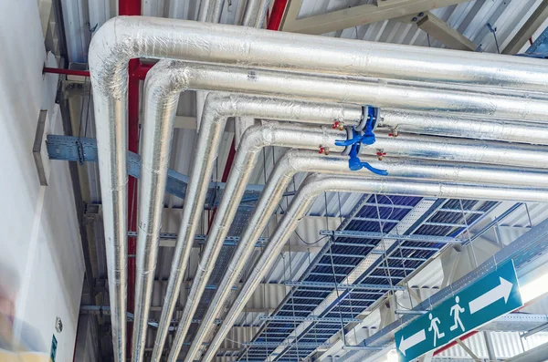 Tavan altına monte edilmiş metal borular modern üretim tesisinde termal yalıtım ile kaplıdır.