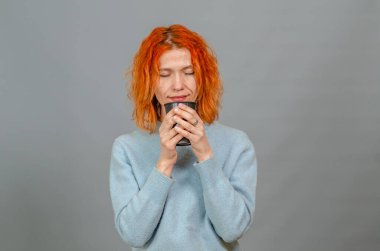 Genç kızıl saçlı, zevkten gözleri kapalı, içki içen kadın.