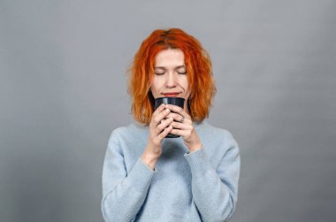 Genç kızıl saçlı, zevkten gözleri kapalı, içki içen kadın.