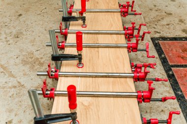 Close up of carpenter fastening board with clamps. Carpentry workshop