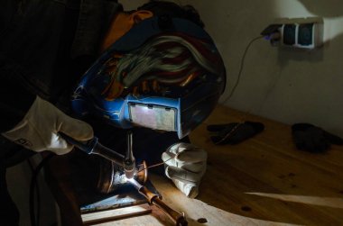 Kaynak işlemi devam ediyor. Onarım. Maske ve eldiven ustası